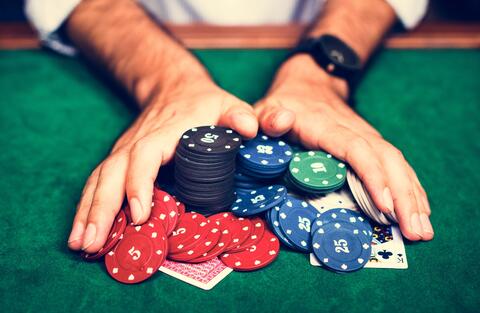 hands pushing poker chips into the center of the table towards the camera