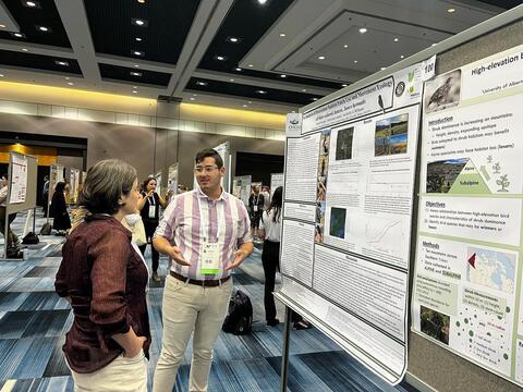 Jacob Morgan presents his poster to a guest.
