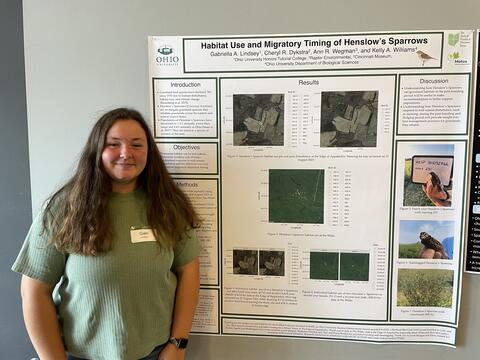 Gabi Lindsey poses smiling in front of her poster.