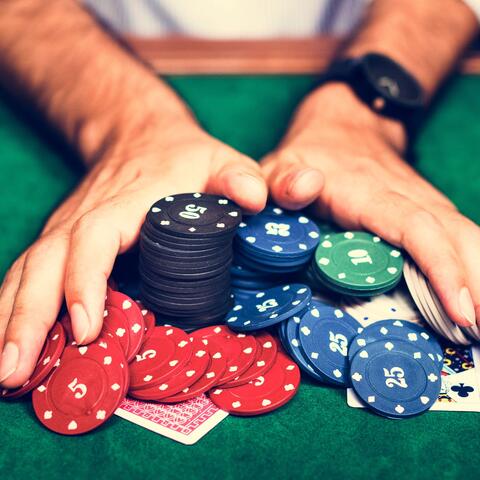 hands pushing poker chips into the center of the table towards the camera